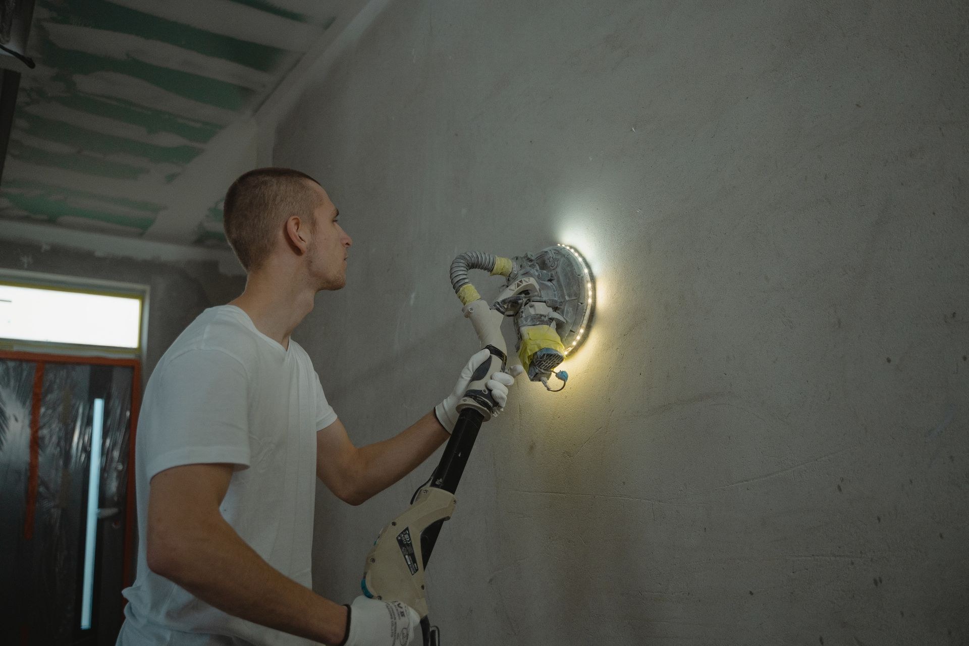 Power sanding a wall to prepare the surface for finishing
